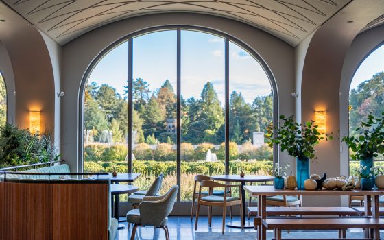 The interior of a restaurant featuring white arched ceilings and wood furniture. 